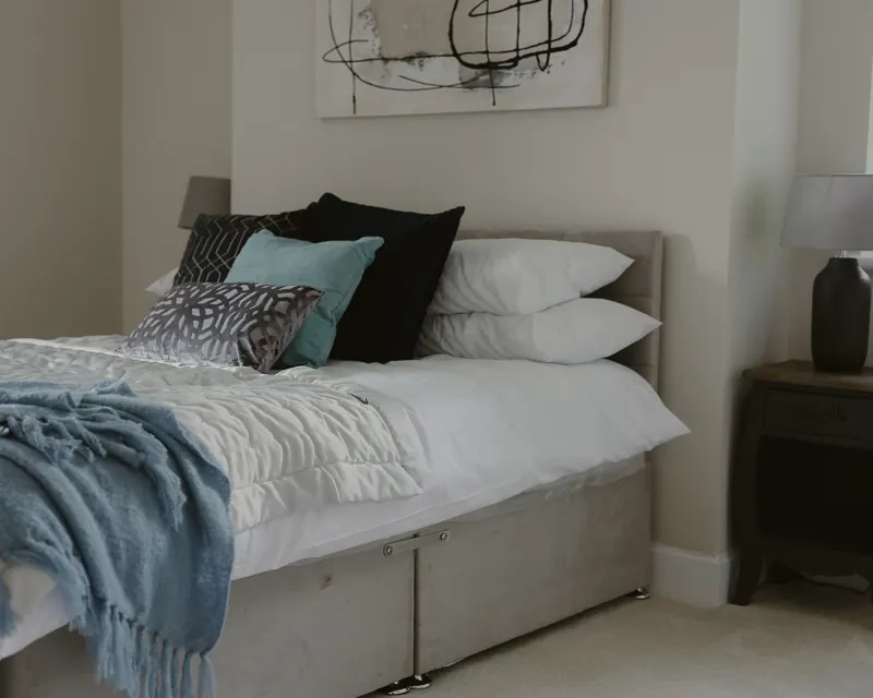 Dressed double bed with cushions and blue throw