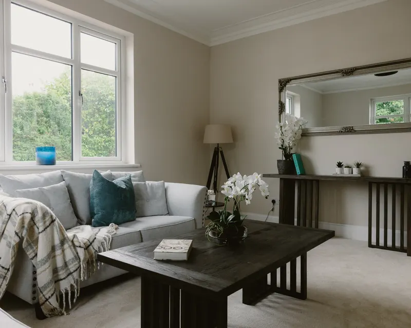Staged living room with grey sofa, dark coffee table and silver mirror