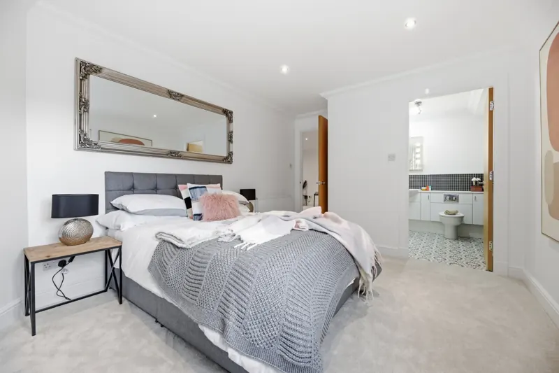 Staged main bedroom with grey headboard and en suite