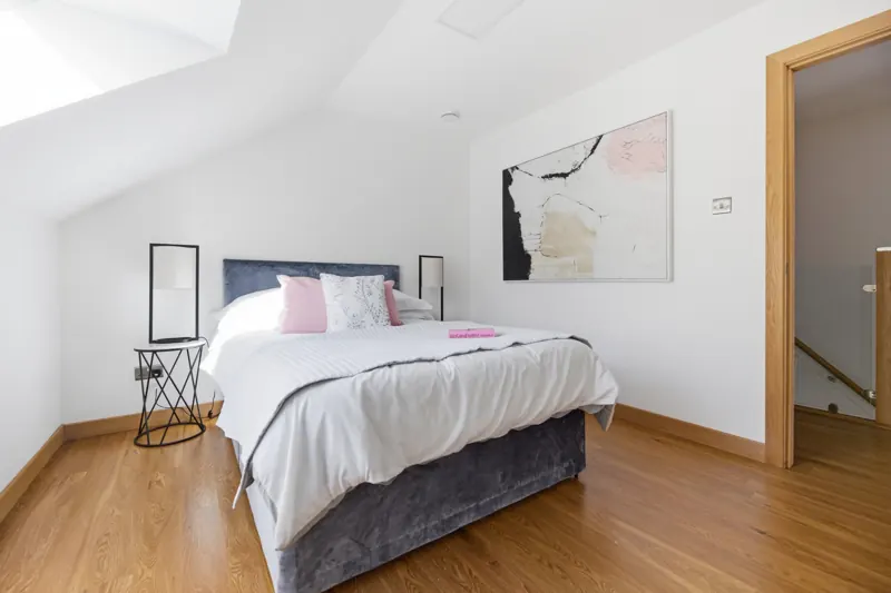 Staged attic bedroom with velvet bed and abstract artwork