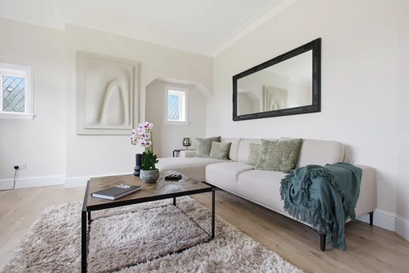 Staged living room with cream corner sofa and teal throw