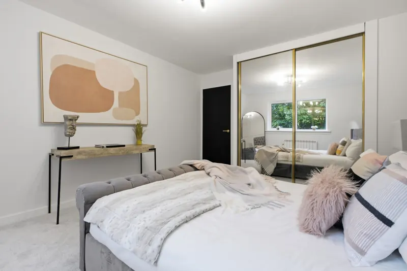 Staged main bedroom with peach artwork and mirrored wardrobes