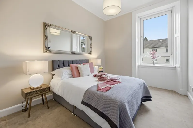 Staged bedroom with tufted headboard and bay window